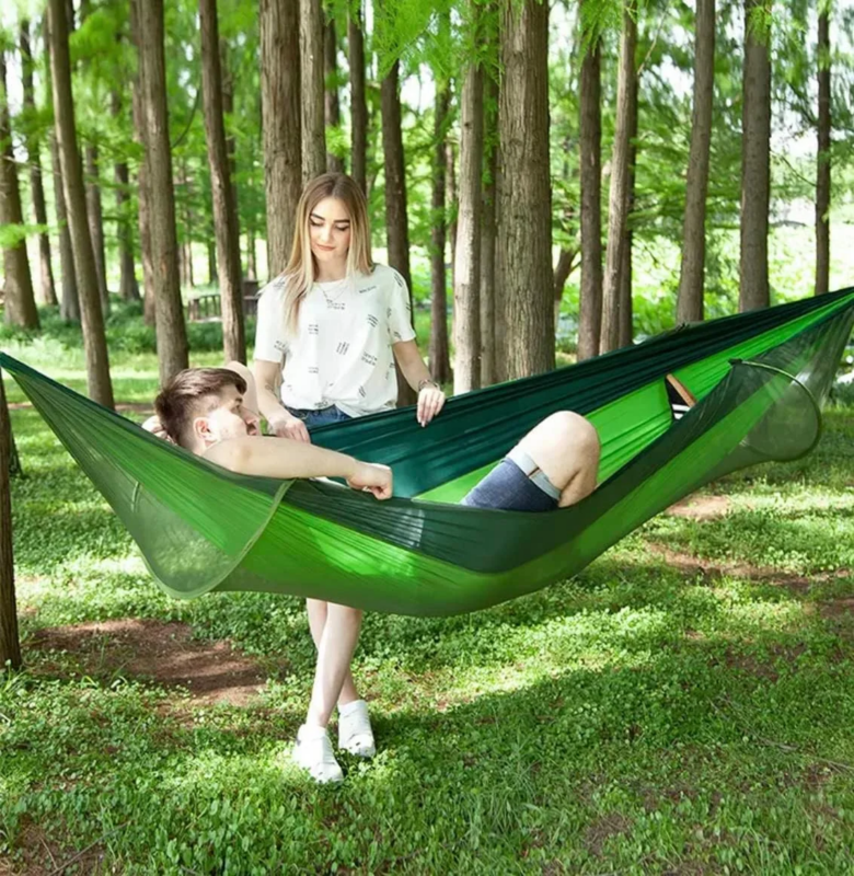 Casal relaxando na hammock com tela anti mosquito durante acampamento
