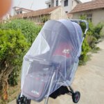 Carrinho de bebé com mosquiteiro instalado para passeio no parque